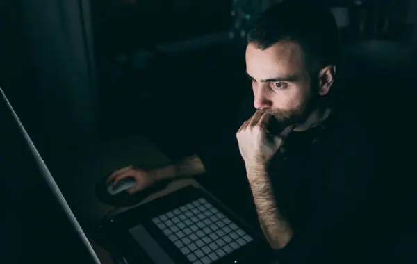 Young man on computer at night looking up secret websites to make money online.